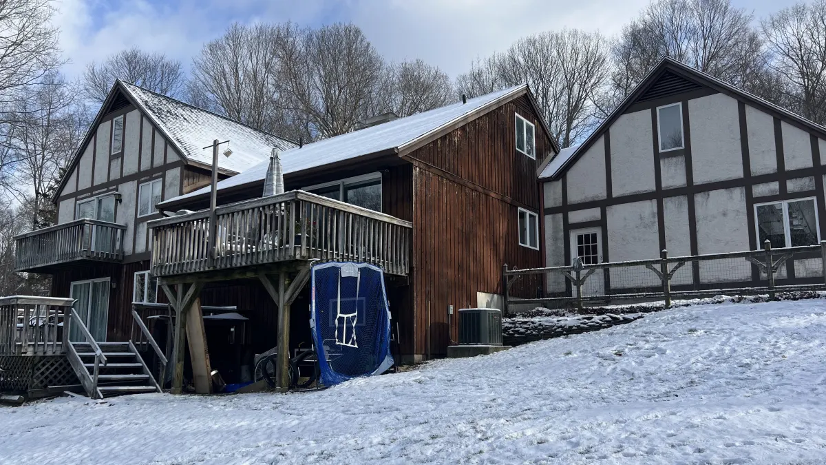 Before - stucco and dark timber Tudor exterior with an aging rear deck on a Southbury, CT home